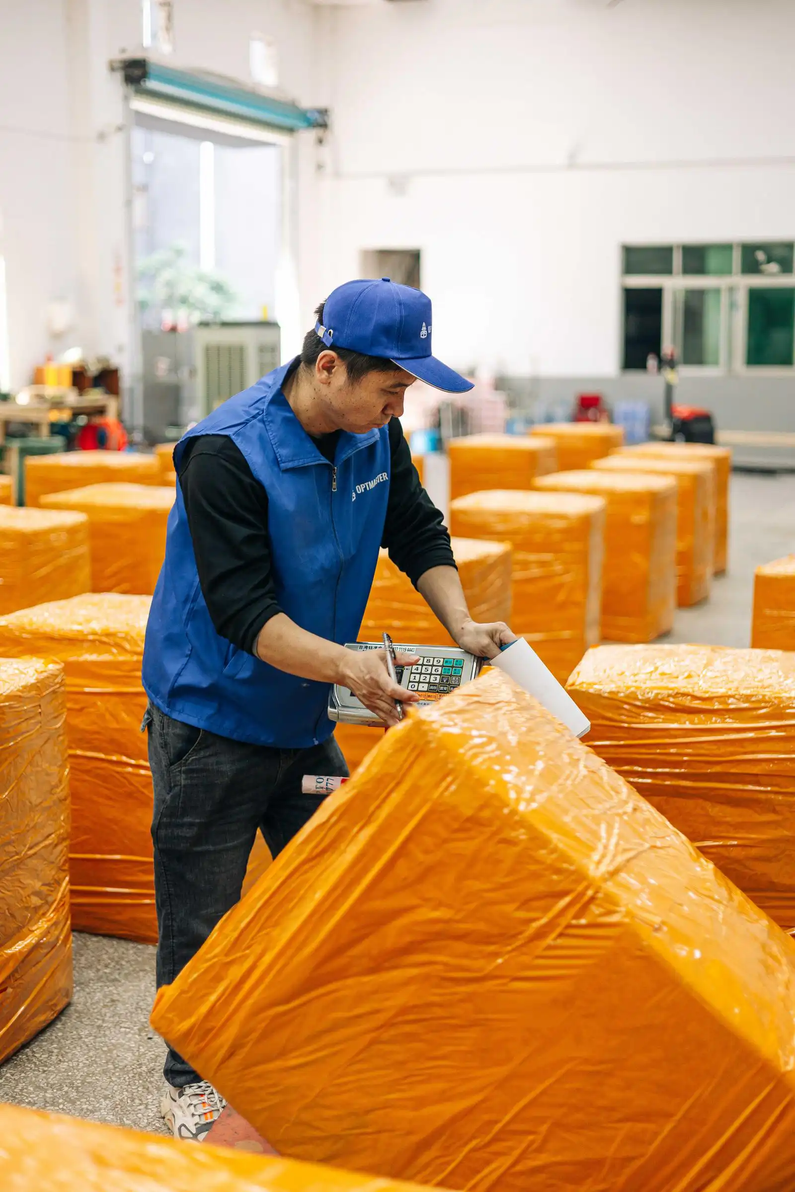 Сотрудник OptMaster в синей форме проверяет упакованный груз на складе в Гуанчжоу, Китай.